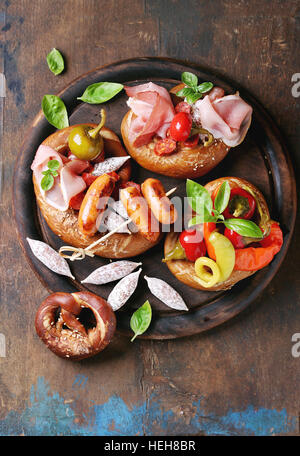 Variété de collations de viande, saucisses frites wienerwurst, jambon, piments marinés servis dans les Bretzels salés avec le basilic sur planche bois ove Banque D'Images