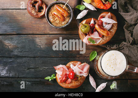 Variété de collations de viande, saucisses frites wienerwurst, jambon, piments marinés servis dans les Bretzels salés avec du basilic frais et un verre de bière blonde ov Banque D'Images