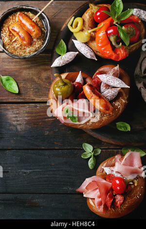 Variété de collations de viande, saucisses frites wienerwurst, jambon, piments marinés servis dans les Bretzels salés avec le basilic sur planche bois ove Banque D'Images