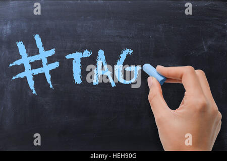 Main femme écrit H tag sur tableau noir avec craie bleu Banque D'Images