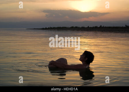 Femme flotte dans la mer Morte, Jordanie, au coucher du soleil Banque D'Images