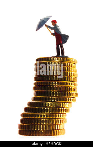 Femme debout Miniature sur une pile de pièces, l'ouverture d'un parapluie Banque D'Images