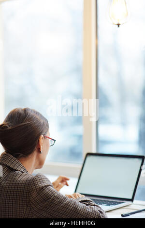 Femme moderne assis en face de l'ordinateur portable dans un café Banque D'Images