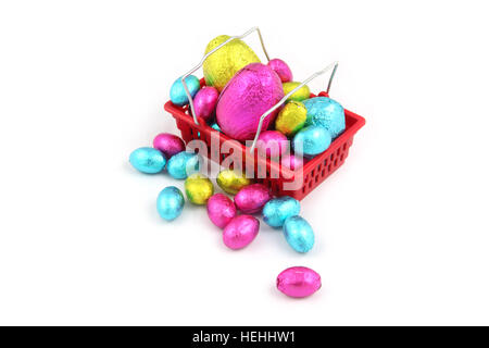 Oeufs de Pâques en chocolat coloré aluminium rétractable, et assis dans un panier à partir d'un super marché sur un fond blanc. Banque D'Images