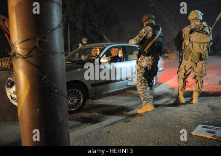 Un policier national iraquien de la 8e Brigade, 2e Division parle aux occupants d'une voiture arrêtée à un point de contrôle de la circulation, alors qu'un soldat américain du 2e Bataillon du 505th Parachute Infantry Regiment, 3e Brigade Combat Team, 82e Division aéroportée, fournit la sécurité, dans Muhallah Beladiyat, 734, l'est de Bagdad, l'Iraq, le 8 janvier, 2009. Une opération menée conjointement avec la police nationale irakienne à la base d'opérations avancée 144318 Fidélité Banque D'Images