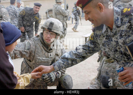 Le lieutenant-colonel Louis Zeisman, originaire de Fayetteville, N.C., commandant du 2e Bataillon du 505th Parachute Infantry Regiment, 3e Brigade Combat Team, 82nd Airborne Division, la Division multinationale de Bagdad et un agent de la Police nationale irakienne donner un garçon irakien des bonbons lors d'un événement de distribution de fournitures scolaires au 19 février Al Assal la maternelle dans la ville de Oubaidy. Le Al Assal La maternelle a été l'une des deux écoles de recevoir des éléments de l'école de l'ensemble des forces canadiennes. Les parachutistes ont aidé leurs partenaires irakiens dans Oubaidy et à Bagdad pendant plusieurs semaines pour améliorer la vie Banque D'Images