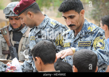 Le Brigadier-général de la police nationale irakienne Ali Ibraheem Dabown, commandant de la 8e brigade, 2e Division, la police nationale irakienne, donne des bonbons aux enfants dans Beladiyat locaux, l'est de Bagdad, l'Iraq, le 12 avril 2009. La police nationale irakienne et les soldats du 2e Bataillon du 505th Parachute Infantry Regiment, 3e Brigade Combat Team, 82e Division aéroportée, sont la distribution de jouets et de bonbons dans la région. La distribution de bonbons et de jouets dans Beladiyat 166383 Banque D'Images