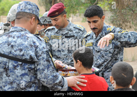 Le Brigadier-général de la police nationale irakienne Ali Ibraheem Dabown (droite), commandant de la 8e brigade, 2e Division, la police nationale irakienne, donne des bonbons aux enfants dans Beladiyat locaux, l'est de Bagdad, l'Iraq, le 12 avril 2009. La police nationale irakienne et les soldats du 2e Bataillon du 505th Parachute Infantry Regiment, 3e Brigade Combat Team, 82e Division aéroportée, sont la distribution de jouets et de bonbons dans la région. La distribution de bonbons et de jouets dans Beladiyat 166400 Banque D'Images