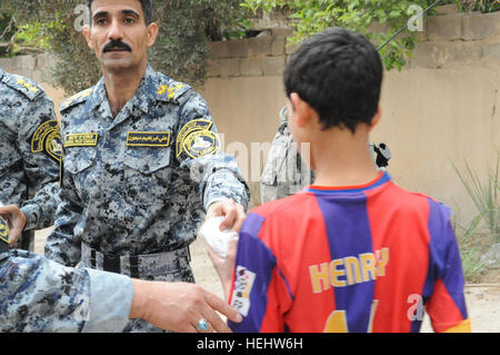 Le Brigadier-général de la police nationale irakienne Ali Ibraheem Dabown, commandant de la 8e brigade, 2e Division, la police nationale irakienne, donne des bonbons aux enfants dans Beladiyat locaux, l'est de Bagdad, l'Iraq, le 12 avril 2009. La police nationale irakienne et les soldats du 2e Bataillon du 505th Parachute Infantry Regiment, 3e Brigade Combat Team, 82e Division aéroportée, sont la distribution de jouets et de bonbons dans la région. La distribution de bonbons et de jouets dans Beladiyat 166392 Banque D'Images