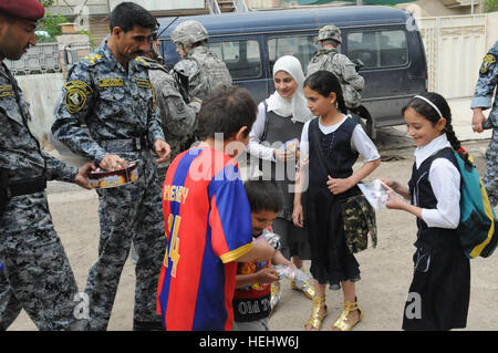 Le Brigadier-général de la police nationale irakienne Ali Ibraheem Dabown, commandant de la 8e brigade, 2e Division, la police nationale irakienne, donne des bonbons aux enfants dans Beladiyat locaux, l'est de Bagdad, l'Iraq, le 12 avril 2009. La police nationale irakienne et les soldats du 2e Bataillon du 505th Parachute Infantry Regiment, 3e Brigade Combat Team, 82e Division aéroportée, sont la distribution de jouets et de bonbons dans la région. La distribution de bonbons et de jouets dans Beladiyat 166384 Banque D'Images