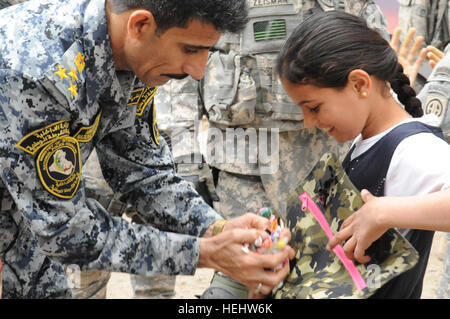 Le Brigadier-général de la police nationale irakienne Ali Ibraheem Dabown, commandant de la 8e brigade, 2e Division, la police nationale irakienne, donne des bonbons à une petite fille, dans Beladiyat iraquien, l'est de Bagdad, l'Iraq, le 12 avril 2009. La police nationale irakienne et les soldats du 2e Bataillon du 505th Parachute Infantry Regiment, 3e Brigade Combat Team, 82e Division aéroportée, sont la distribution de jouets et de bonbons dans la région. La distribution de bonbons et de jouets dans Beladiyat 166395 Banque D'Images