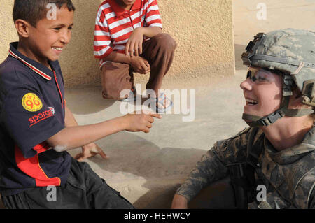 Un garçon irakien local partage un rire avec Spc de l'armée américaine. Nicole Willson de Hillsdale, Mich., infirmier du Quartier général et l'entreprise de l'Administration centrale, 3e Brigade Combat Team, 82e Division aéroportée, dans l'al-Madain Région de l'est de Bagdad, l'Iraq, le 18 avril 2009. Des soldats américains sont dans le domaine de l'évaluation des terrains de soccer, et la distribution de ballons de soccer a fait don à la mémoire d'un soldat américain tombé, la FPC. Nick Madaras. L'oeil sur al-Madain 166506 Banque D'Images