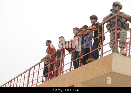 Un soldat américain de la 3e Brigade Combat Team, 82e Division aéroportée, et des garçons irakiens s'appuyer sur une balustrade de l'est donnant sur un terrain de soccer à l'Est, Karadah Bagdad, l'Iraq, le 8 mai. L'iraquien local public était invité à regarder un match de football de la jeunesse suivie d'un match entre des équipes conjointes de soldats américains de la 3e Brigade Combat Team, 82e Division aéroportée, et la police nationale irakienne. Match de football à Bagdad, Iraq 172299 Banque D'Images