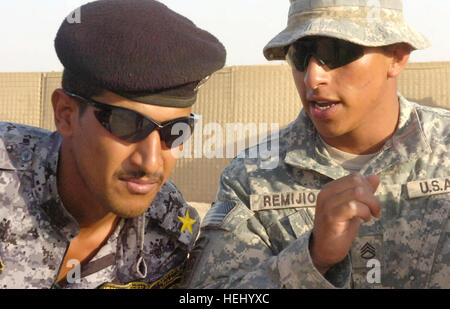 Le s.. Damian Remijio, de Chicago, affecté à l'escadron de troupes K, 5e, 73e de cavalerie, 82e Division aéroportée, Multi-National Division-Baghdad, conseille un lieutenant de la Police nationale sur les procédures tactiques pendant une opération de nettoyage à l'événement de formation le 24 juin à la base d'opérations avancée marteau, Iraq, situé à l'extérieur de l'est de Bagdad. Les IP attribuées à la 3e Brigade, 1NP NP Division sont actuellement en formation au cours d'un cycle de formation de deux semaines en vertu de l'escadron, nouveau "Panther Recon Training Academy." Les deux semaines de former et d'encadrer l'académie de l'escadron des Forces de sécurité irakiennes partenaires sur Banque D'Images