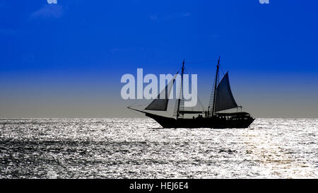 Photo montrant un voilier sur mer naviguer vers le coucher du soleil. L'image a été prise dans la mer des Caraïbes. Banque D'Images