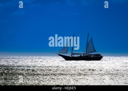 Photo montrant un voilier sur mer naviguer vers le coucher du soleil. L'image a été prise dans la mer des Caraïbes. Banque D'Images