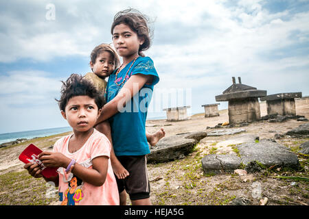 Enfants d'âge scolaire prenant soin d'un bébé dans le village de Ratenggaro, île de Sumba, province de Nusa Tenggara est, Indonésie. Banque D'Images