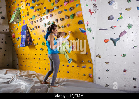 Les jeunes femmes d'aider l'instructeur d'escalade grimper garçon mur artificiel Banque D'Images