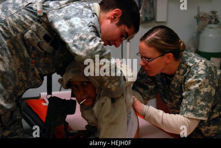 Une 33e Infantry Brigade Combat Team medic aide les 1er lieutenant Susan Moore, aussi un infirmier de l'IBCT 33e, tandis que les shes des chèques de plus un jeune garçon Afghan cicatrices à la clinique médicale de troupes au camp Phoenix, Kaboul, Afghanistan. Le garçon a été portée à la clinique après des plaintes de douleur. Photo de l'Armée américaine par la CPS. Luke S. Austin, photojournaliste pour fournir des soins infirmiers de l'armée afghane locale 141864 Enfants Banque D'Images