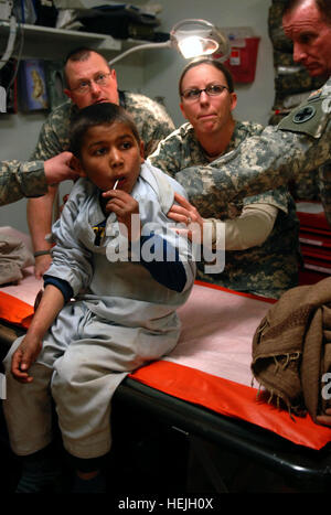 (L à R) Sgt. David Hergett, 1er lieutenant Susan Moore, médecins avec la 33e Brigade d'infanterie, l'équipe de combat et le Major Robert Bailey, un médecin avec la 33e IBCT, regardez plus de vieilles cicatrices sur un Afghan dos du garçon à la clinique médicale de troupes au camp Phoenix, Kaboul, Afghanistan. Le garçon a été portée à l'TMC après il s'est plaint de douleur de ses blessures cicatrisées. Photo de l'Armée américaine par la CPS. Luke S. Austin, photojournaliste infirmiers de l'Armée de fournir des soins aux enfants afghans locaux 141863 Banque D'Images