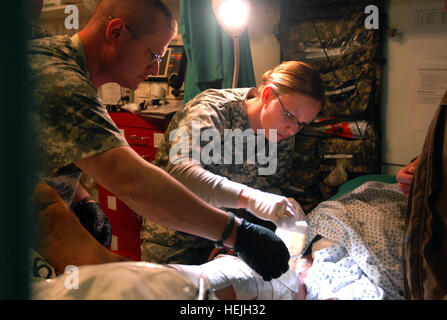 Le Sgt. David Hergett et 1er lieutenant Susan Moore, médecins avec la 33e équipe de combat d'infanterie, déposer des bandages sur un garçon afghan local est brûlé à la jambe la clinique médicale de troupes au camp Phoenix, Kaboul, Afghanistan. Le garçon a été portée à l'essence après TMC sur sa jambe a pris feu, causant de graves brûlures. Photo de l'Armée américaine par la CPS. Luke S. Austin, photojournaliste infirmiers de l'Armée de fournir des soins aux enfants afghans locaux 141862 Banque D'Images