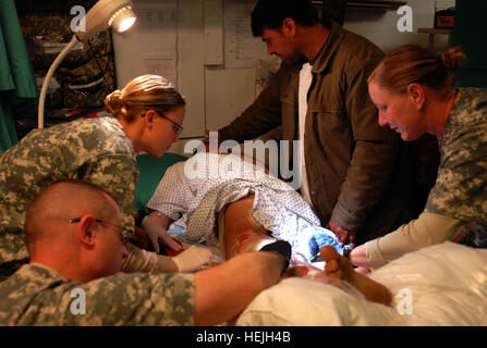 (L à R) Medecins 1er lieutenant Susan Moore, Sgt. David Hergett et le Sgt. 1re classe Tammy Genovese, l'Infanterie de la 33e Brigade Combat Team, retirer tissu mort d'un garçon afghan local comme la jambe de son père. Alors qu'au travail à un point de carburant à Kaboul, Afghanistan, le garçon carburant répandu sur sa jambe, qui plus tard a pris feu à son domicile. Il a été conduit à la clinique médicale de la troupe au camp Phoenix ici pour les soins. Photo de l'Armée américaine par la CPS. Luke S. Austin, photojournaliste infirmiers de l'Armée de fournir des soins aux enfants afghans locaux 141866 Banque D'Images