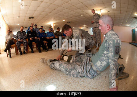 Les médecins de l'armée américaine avec 1er bataillon du 504e Parachute Infantry Regiment, 82nd Airborne Division (Brigade) conseiller et assister les policiers iraquiens montrer comment bien l'attelle une jambe lors d'un cours de base Gareautrain dans Village touristique de Habbaniyah, Al Anbar province, l'Iraq, le 6 octobre. Les médecins de l'Armée de terre adaptée aux techniques de combat gareautrain aux besoins et aux ressources de la propriété intellectuelle. Apprendre la police iraquienne en sauvetage de Paratrooper Medecins 212518 Banque D'Images