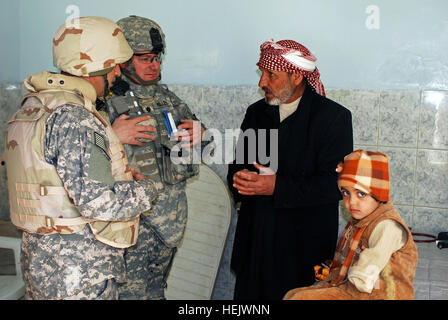 Le lieutenant-colonel Robert Miller, un fournisseur médical avec 2e Bataillon, 23e Régiment d'infanterie, 4e Stryker Brigade Combat Team, 2e Division d'infanterie de Fort Lewis, Washington, parle à un homme de l'Iraq à propos de ses filles bras manquants, à un engagement médical dans O'couba, Iraq, 10 févr. 29. IA,des soldats des FC de fournir gratuitement healtcare à O'couba 78800 citoyens Banque D'Images