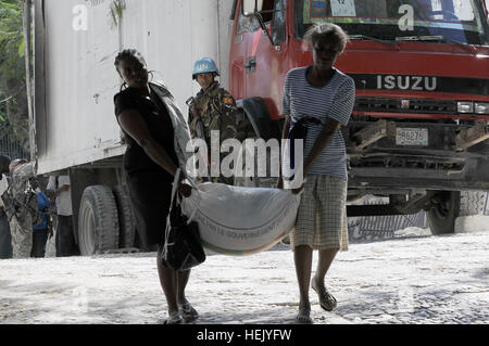 Une lutte de deux femmes haïtiennes pour transporter un sac de 50 kg de riz qu'elles ont reçu de la nourriture des distrobution point, le 1 février, à Port-au-Prince, Haïti. Les organisations de l'alimentation en Haïti convergent avec l'armée américaine lors de l'opération réponse unifiée de fournir une aide à l'effort humanitaire massive menée tout au long du séisme qui a dévasté Haïti. (U.S. Photo de l'Armée de combat par Maître Photographe Sgt. Martin Cervantez/libérés) Opération Réponse unifiée 246661 Banque D'Images