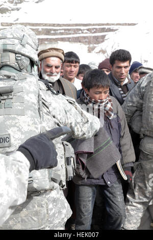 Les enfants afghans locaux et les adultes attendent leur tour de recevoir des biens de l'armée américaine pour les mois d'hiver. Les marchandises sont remises par la société MP 410th, du Texas, sur la route qui mène à la passe de Salang, près du tunnel de Salang, la province de Parwan, Afghanistan, le 10 février. L'opération Enduring Freedom 250317 Banque D'Images