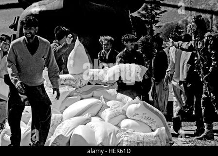 Les Pakistanais Local décharger sacs de farine livré par un Denali TF hélicoptère CH-47 Chinook de kalam, une zone d'atterrissage dans les inondations de la vallée de Swat, province de Khyber Pakhtunkhwa, au Pakistan. 'Bears' au Pakistan, le 'vol' et 'aider les gens' 338400 Banque D'Images