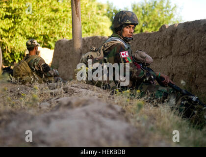 Les commandos afghans, avec l'Armée nationale afghane par le 3e Kandak de commando, d'utiliser un mur pour couvrir et de dissimulation tout en assurant la sécurité du périmètre pour une patrouille arrêtée au cours d'une opération de déminage du village dans le district de Shah Wali Kot, le 3 juillet, la province de Kandahar, Afghanistan. Les commandos, assisté de U.S. Navy SEALs avec Special Operations Task Force - Au sud, ont été rejoints par le commandant 3e Kandak Commando, le Colonel Mohammad Akbar, Shah Wali Kot et chef de police de district, Bacha Khan. Les joints de commandos, continuer la lutte pour Kandahar 424671 Banque D'Images