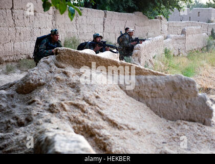 Les commandos afghans, avec l'Armée nationale afghane par le 3e Kandak de commando, d'utiliser un mur pour couvrir et de dissimulation après avoir pris feu de l'ennemi au cours d'une opération de nettoyage du village dans le district de Zhari, le 6 juillet, la province de Kandahar, Afghanistan. Les commandos, appuyés par les membres du service des opérations spéciales avec groupe de travail - Sud, trouvé et détruit plusieurs caches composé d'explosifs artisanaux et matériaux d'EEI, ainsi qu'une cache d'armes. Nous sortons de commandos, trouver des caches à Kandahar, 425148 Banque D'Images