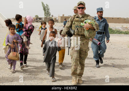 Le sergent de l'armée américaine. 1re classe Chris Barnes, dirige un groupe d'enfants à une aire locale où la police en uniforme afghane et de la Police nationale afghane de l'ordre civil ont mis en place des tables pour aider les enfants à faire des cerfs-volants dans un village près de l'aérodrome de Kandahar, Afghanistan, le 17 juillet 2011. L'ANCOP AUP et faire des cerfs-volants avec les enfants et de distribuer des livres, des jouets, des chaussettes et des bonbons. La conduite de la police afghane de l'activité de cerfs-volants avec des enfants afghans 110717-A-DM450-002 Banque D'Images