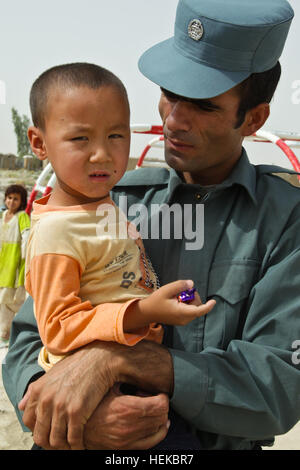 Un agent de police en uniforme afghane parle avec un petit garçon au cours d'une activité de construction de cerfs-volants dans un village près de l'aérodrome de Kandahar, Afghanistan, le 17 juillet 2011. La Police en uniforme afghane et l'Afghan National Civil Order Police fait des cerfs-volants avec les enfants et de distribuer des livres, des jouets, des chaussettes et des bonbons. La conduite de la police afghane de l'activité de cerfs-volants avec des enfants afghans 110717-A-DM450-045 Banque D'Images