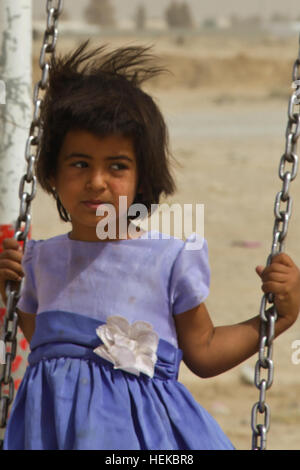 Une petite fille joue sur un swing lors d'un kite de décisions mise en place de l'activité par la police en uniforme afghane et de la Police nationale afghane de l'ordre civil dans un village près de l'aérodrome de Kandahar, Afghanistan, le 17 juillet 2011. L'ANCOP AUP et faire des cerfs-volants avec les enfants et de distribuer des livres, des jouets, des chaussettes et des bonbons. La conduite de la police afghane de l'activité de cerfs-volants avec des enfants afghans 110717-A-DM450-042 Banque D'Images