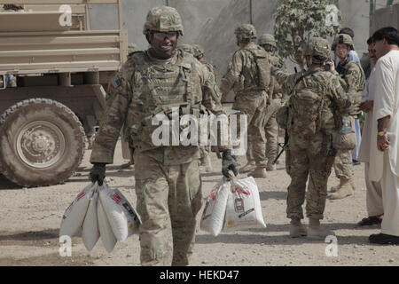 Le sergent de l'armée américaine. Thomas, à gauche, à partir de la 58e Compagnie de Police militaire hors de Schofield Barracks, Missouri, transporte un sac de riz du camion au cours d'un parachutage d'aide humanitaire dans la province de Kandahar, Afghanistan, le 29 août 2011. Le riz et d'autres fournitures ont été donnés aux sections locales que l'aide humanitaire dans l'espoir de renforcer la sécurité, la gouvernance et la stabilité dans la région. Des soldats de la 58e Compagnie de Police militaire fournie à l'appui du centre-ville de Labour Force opérationnelle dans la partie nord de la ville de Kandahar. (U.S. Photo de l'armée par le Sgt. 1re classe James Fidel/libérés) U.S. Army Sgt. Thomas, à gauche, à partir de 58e milit Banque D'Images