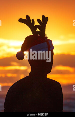 Coucher de soleil sur Crosby, Liverpool, Royaume-Uni. 22 Dec 2016. Météo. L'un des 'hommes' sculptures fer obtient vraiment dans l'esprit de Noël wearing a Santa hat & cornes de renne. Ces sculptures sont spectaculaires sur Crosby Beach près de Liverpool. 'Un autre endroit' par 'célèbre sculpteur Antony Gormley', se compose de 100 Vie en fonte grandeur le long de trois kilomètres de l'estran, qui s'étend près d'un kilomètre au large. © Cernan Elias/Alamy live news Banque D'Images