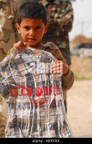 Un enfant irakien, d'un fils de l'Irak, montre son nouveau jouets et vêtements qu'elle a reçu de la part des soldats de l'Administration centrale et de l'Administration centrale, l'entreprise Armor 1er Régiment, 37e Bataillon, 1e Brigade Combat Team, 1st Armored Division à Fort Bliss, au Texas, au cours d'une mission d'aide humanitaire et médicale à la Di siège à Hawijah, près de Kirkouk, Irak, le 24 mars. Famille de SoI recevoir beaucoup besoin d'attention médicale 264095 Banque D'Images