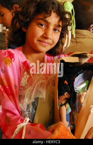 La fille d'un fils de l'Irak, montre ses nouveaux jouets et vêtements qu'elle a reçu de la part des soldats de l'Administration centrale et de l'Administration centrale, l'entreprise Armor 1er Régiment, 37e Bataillon, 1e Brigade Combat Team, 1st Armored Division à Fort Bliss, au Texas, au cours d'une au cours d'une mission d'aide humanitaire et médicale à la Di siège à Hawijah, près de Kirkouk, Irak, le 24 mars. Famille de SoI recevoir beaucoup besoin d'attention médicale 264096 Banque D'Images