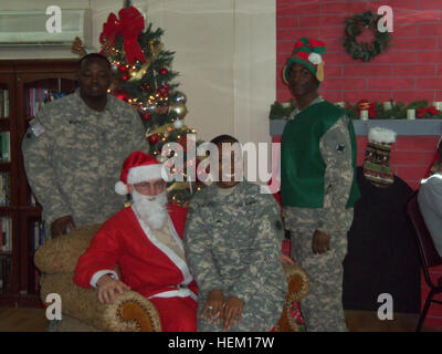 La FPC. Blanc (à gauche) et le Sgt. Dampier (les genoux du Père Noël), les soldats du détachement et de l'Administration centrale l'Administration centrale, 112e Bataillon de la Police militaire, prendre une photo avec le Père Noël et son aide à l'entreprise fête de Noël. 505089 Noël au Koweït Banque D'Images