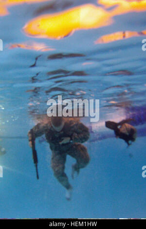 Un soldat avec B Troop, 6e Escadron, 8e régiment de cavalerie, d'infanterie 4e Brigade Combat Team, 3e Division d'infanterie, tente de supprimer un vest juste sous la surface de l'eau après avoir plongé les yeux bandés dans une piscine, le 5 janvier, au cours de la lutte contre la formation de survie en eau à Fort Stewart, Ga. ? ? ? ? ? ? ?Bushmaster ? ? ? ? ? ? ? Soldats transportés des armes factices en nageant la longueur de la piscine et créé à l'aide de dispositifs de flottaison pantalon ACU. Un soldat américain avec Bravo Troop, 6e Escadron, 8e régiment de cavalerie, l'équipe de combat de la 4e Brigade d'infanterie, 3ème Division d'infanterie tente de retirer une charge-b Banque D'Images