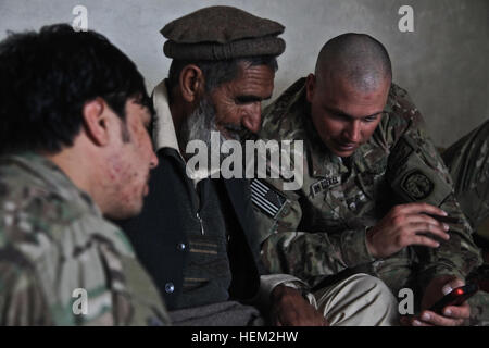 La 1ère Armée américaine Sgt. Christopher Van Roekel (à droite), du centre de Guthrie, Iowa, servant avec 549e Compagnie de Police Militaire, Groupe de travail Raider, partage des photos personnelles avec un Afghan ancien et un interprète à l'intérieur d'un composé de la police en uniforme afghane, dans le district de Dur Baba, province de Nangarhar, Afghanistan, le 13 février 2012. Le but de la mission était d'effectuer un des dirigeants-clés de l'engagement avec le district de Dur Baba sous-gouverneur pour discuter de la fermeture de la milice locale du programme. La Police en uniforme afghane patrouille ANA 120213-A-LP603-060 Banque D'Images