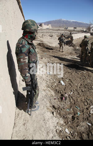 Un soldat de l'Armée nationale afghane observe alors que des soldats américains du 2e peloton, Compagnie D, 3e bataillon du 509e Airborne Brigade Combat Team, Groupe de travail Spartan, patrouille dans le ville de Kolagu, Paktiya province, l'Afghanistan, le 8 mars 2012. Prendre un pas en arrière pour laisser les forces nationales afghanes prendre la tête lors de l'opération Khoti Kheyl pour faire progresser leur présence dans toute la province et démontrer leur force et leurs capacités. Opération Khoti Kheyl 120308-A-XF428-072 Banque D'Images