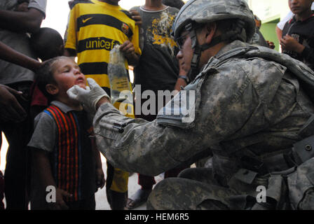 La CPS. Nicholas Cisneros, un infirmier de combat et siège de l'entreprise de l'Administration centrale, 1er Bataillon, 37e Armor, 1e Brigade Combat Team, 1st Armored Division à Fort Bliss, Texas, fournit une aide médicale à un jeune garçon irakien avant la coupe du ruban pour Al Bassa pour l'école primaire, dans le village de Tal Jal, au nord-ouest d'Hawijah, l'Iraq, le 6 juillet. Aider les filles soldats Texas donner lieu à apprendre 297388 Banque D'Images