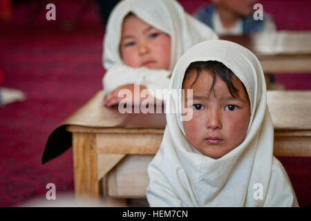 La province de Bamyan, Afghanistan - une petite fille à l'écoute de son professeur pendant un cours au Studio Arzu espoir composé dans le Dragon Valley à l'ouest de la ville de Bamyan. Les femmes et les enfants inscrits au programme sont enseignées les compétences de tisser des tapis, et sont tenus d'assister aux cours d'alphabétisation. Les femmes ont également accès aux services de garde pour leurs enfants, de l'eau chaude pour laver les vêtements, d'une cuisine, et un jardin où ils peuvent cultiver leurs propres légumes et herbes. Les enfants plus âgés suivent des cours avant et après l'apprentissage des techniques de tissage. (U.S. Photo de l'armée par le Sgt. Ken cicatrice, Mobile 7e Détachement des affaires publiques Banque D'Images