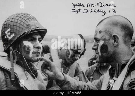 Des soldats américains, y compris Jake McNiece, droite, affecté à la 101e Division aéroportée appliquer la peinture de la guerre à l'autre ?s face à l'Angleterre le 5 juin 1944, en vue de l'invasion de la Normandie, la France, le jour suivant. Le matin du 6 juin 1944, les forces alliées a mené un assaut aéroporté massive et de débarquement amphibie en Normandie de la France. L'invasion a marqué le début de la phase finale de la Seconde Guerre mondiale en Europe, qui a pris fin avec la capitulation de l'Allemagne au mois de mai suivant. McNiece a dirigé un groupe appelé la démolition 13 Sales, dont les exploits ont été portés à l'inspiriation de Banque D'Images