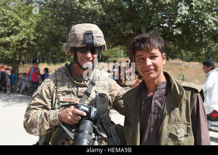 U.S. Air Force capitaine principal Sgt. Dale Canotari servant avec le 455 e Escadron expéditionnaire des Forces de sécurité "Moissonneurs" et un garçon afghan posent pour une photo à l'extérieur d'un composé de la Police nationale afghane dans la province de Parwan, à l'Afghanistan, du 22 septembre 2012. Canotari document Aide pour le 455 e Escadron des Forces de sécurité de la Force expéditionnaire du Canada. (U.S. Photo de l'armée par la CPS. Claire Andrew Baker/libérés) composé de l'ANP 120922-A-NI188-087 Banque D'Images