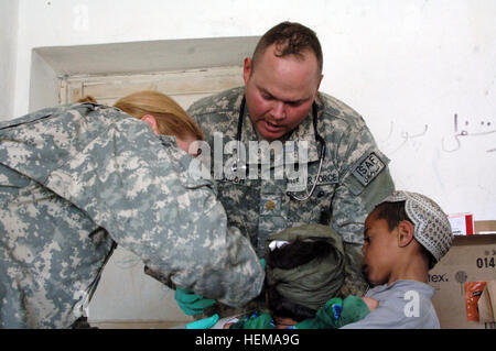 Le 30 avril, 2007 Un jeune garçon tient sa soeur comme le Major Tim Gacioch, un médecin de l'Équipe de reconstruction provinciale de Bagram, examine ses mains gravement brûlé à la medcap mené dans une école du district de Tagab de la province de Kapisa, en Afghanistan. Photo de l'Armée américaine par Michael Bracken autorisé pour diffusion publique par le major John N. Bryan APN Afghanistan PAO DSN - 318.231.4448 L'opération Enduring Freedom 44127 Banque D'Images