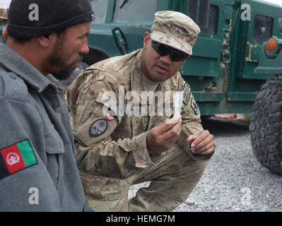 Le sergent de l'armée américaine. Bennett Samson, un infirmier de l'équipe d'assistance aux forces de sécurité 21, 29th Infantry Brigade Combat Team, New York National Guard, apprend à un policier afghan avec le bataillon de réserve, Qalat à propos de décompression à l'aiguille au cours d'un Combat épargnant de vie classe à Qalat dans province de Zabul, Afghanistan, 3 avril 2013. Les policiers vont former le reste de leur bataillon, à l'aide première tactique dans les mois à venir. (U.S. Photo de l'armée par la CPS. Tim Morgan et de la police en uniforme afghane) Parution devenir Life Savers 904774 Combat Banque D'Images